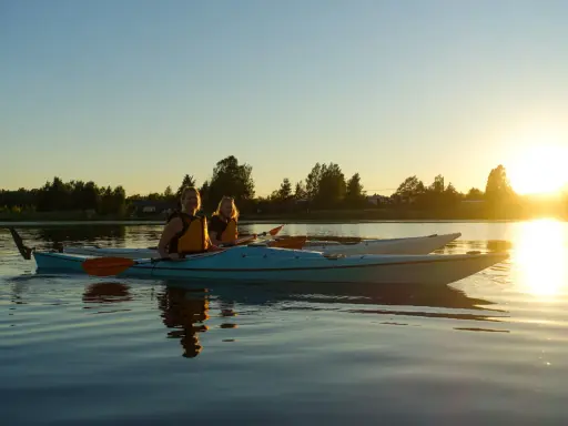 Två kvinnor i kajak njuter av solnedgången vid en sjö nära Karlstad.