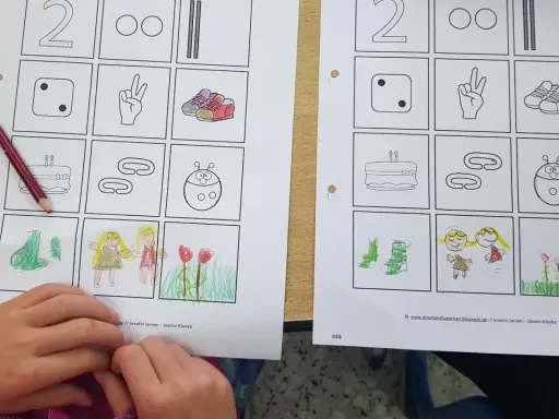 Arbeitsblatt mit binnendifferenzierung beispielen: Zahlen, Würfel, Schuhe, Kuchen, Marienkäfer, Blumen und Kinder. Ein Kind malt.