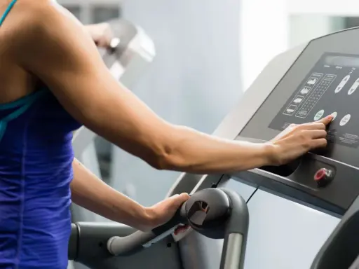 Frau stellt Steigung für ihr **incline walking** auf dem Laufband ein.
