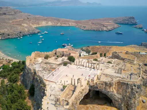 Akropol w Lindos na Rodos, z widokiem na turkusową zatokę i plażę. Wspaniałe ruiny przypominają o dawnej świetności, a nie o koszmarze.