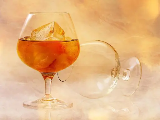Kieliszek z brandy i lodem, obok pusty, przewrócony kieliszek. Idealny sposób, jak pić brandy.