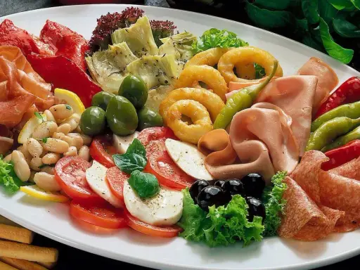 Eine üppige Platte mit italienischen Vorspeisen: Prosciutto, Salami, Mozzarella, Tomaten, Oliven, Artischocken, Bohnen und eingelegte Paprika.