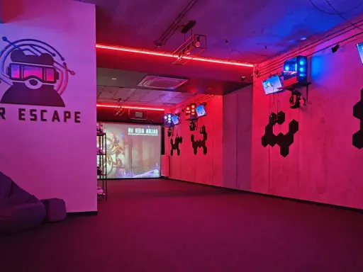 Częstochowa escape room z neonowym oświetleniem, logo VR ESCAPE i ekranem projekcyjnym.