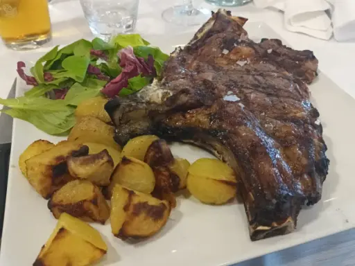 Costata di manzo succulenta con patate arrosto e insalata fresca, un piatto da re.