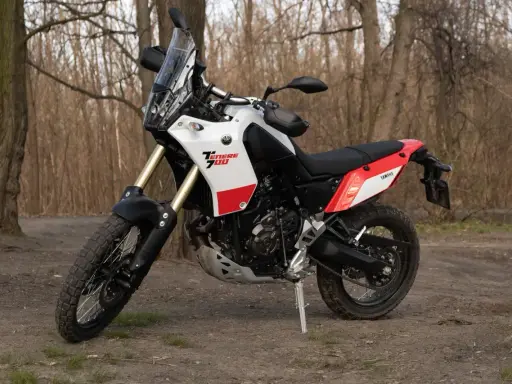 Yamaha Tenere 700 waga idealna na wyprawy. Motocykl stoi na leśnej ścieżce, gotowy do przygody.