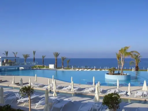 Luksusowy basen z palmami i widokiem na morze. Wiele opinii o King Evelthon Beach Hotel and Resort potwierdza jego piękno.