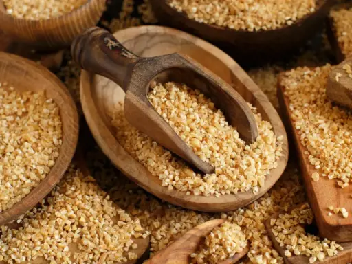 Kasza bulgur w drewnianych misach, gotowa do spożycia. Niski indeks glikemiczny sprawia, że jest zdrowym wyborem.