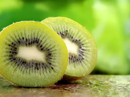 Dwa soczyste kiwi, przekrojone na pół, ukazują swoje zielone wnętrze z czarnymi pestkami. To naturalne kiwi co leczy, pełne witamin.