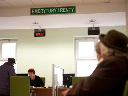 Ludzie czekają na obsługę w urzędzie "Emerytury i Renty". Zastanawiają się, w jakim miesiącu najlepiej przejść na emeryturę.