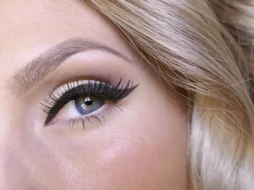 Blått öga med dramatisk eyeliner och voluminösa fransar. Vackert hår som ramar in ansiktet. Det är enkelt att måla sig så här fint.