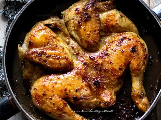 Pollo alla diavola succulento e dorato, cotto in padella con spezie piccanti.