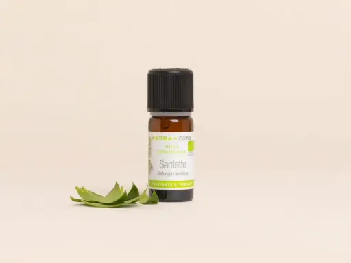 Flacon d'huile essentielle sarriette des montagnes, aux vertus purifiantes et toniques, accompagné de quelques feuilles fraîches.