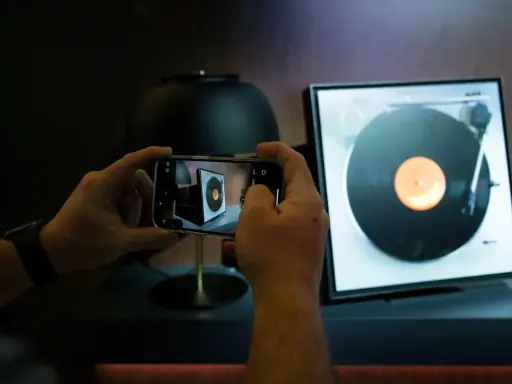 Ręce trzymają smartfon, fotografując gramofon. Odkryj gadżety do domu, o których nie miałeś pojęcia, jak ten nowoczesny sposób na docenienie klasycznej muzyki.