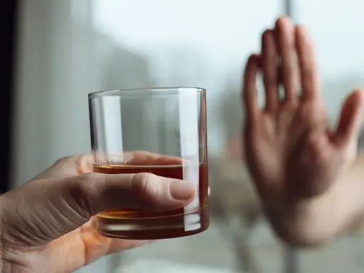 Dłoń odrzuca szklankę z alkoholem, symbolizując decyzję o zerwaniu z nałogiem. To koniec drogi, która mogła prowadzić do zgonu po esperalu.