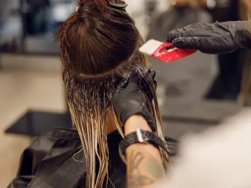 Friseur trägt Farbe auf, um einen sanften Farbverlauf zu erzielen. Die color melting Technik lässt die Töne harmonisch ineinander übergehen.
