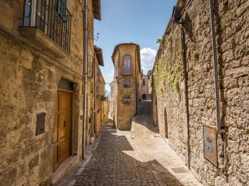 Antica scala di borgo in pietra, con case strette e un cielo azzurro.