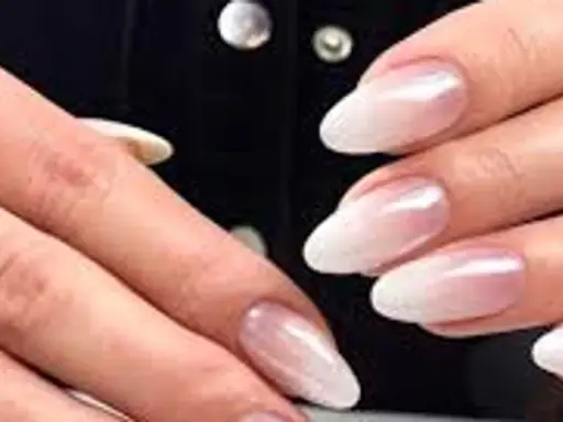 Dłonie z paznokciami w stylu french z pyłkiem, delikatny ombre od różu do bieli, subtelny blask.