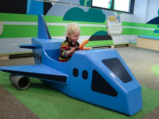 Liten pojke leker i ett blått leksaksplan. En rolig resa med bebis börjar här!