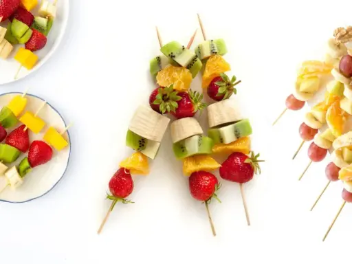 Brochetas de frutas coloridas con fresas, kiwi, plátano, mango, naranja, uvas y nueces. ¡Un postre refrescante y saludable!