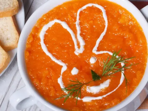 Pomarańczowa marchwianka z ryżem na biegunkę, ozdobiona śmietaną w kształcie królika. Podana z grzankami.