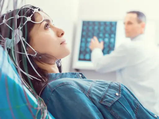 Kobieta w czepku EEG podczas badania VEP. Lekarz analizuje wyniki na ekranie.