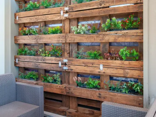 Un **jardín vertical con palets** luce plantas verdes y rojas en un diseño rústico.