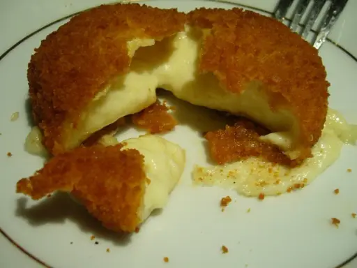Pyszny camembert w panierce, z którego wypływa gorący, ciągnący się ser. Idealna przekąska na ciepło.