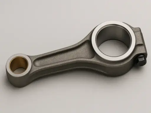 Una biela de motor de metal gris con un casquillo de bronce en un extremo y un perno en el otro.