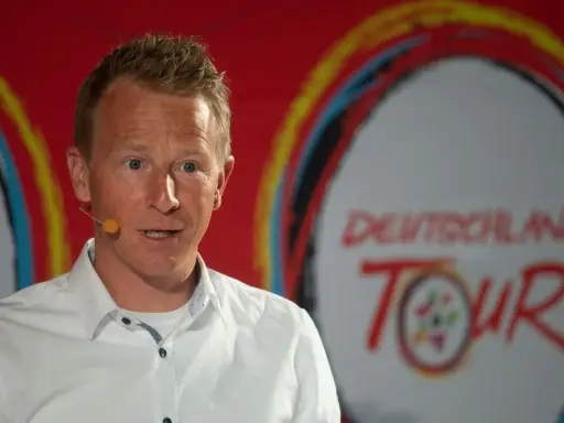 Fabian Wegmann spricht vor dem Logo der Deutschland Tour. Seine Vergangenheit mit Doping-Vorwürfen wirft einen Schatten auf seine Karriere.