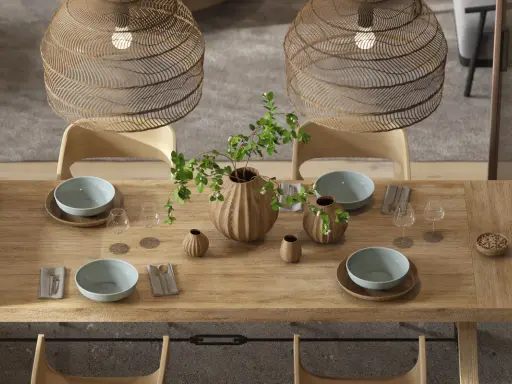 Drewniany stół w jadalni w stylu boho, nakryty do posiłku. Wazon z gałązkami i liśćmi, misy, kieliszki i plecione lampy tworzą przytulną atmosferę.