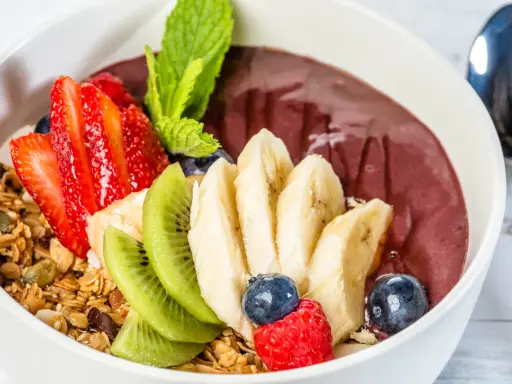 Acai-Schüssel mit Früchten, Granola und einem Hauch von Vitamin C. Erdbeeren, Bananen, Kiwi, Blaubeeren und Himbeeren machen diese Schüssel zu einem gesunden Genuss.