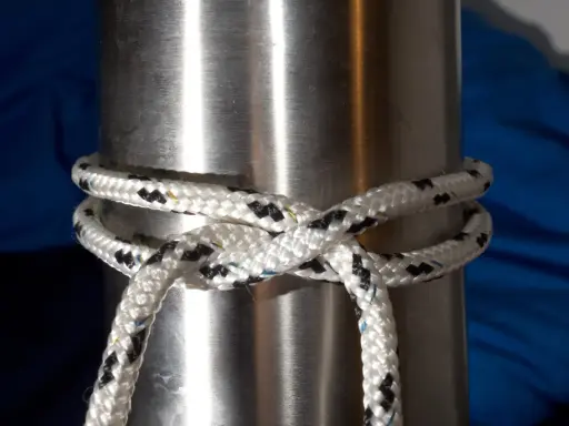 Un nœud pare battage, simple et efficace, sécurise une corde blanche et noire autour d'un mât métallique.