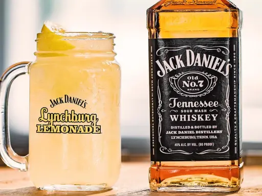En iskallad Jack Daniel's Lynchburg Lemonade i ett glas med handtag, bredvid en flaska Jack Daniel's Tennessee Whiskey.