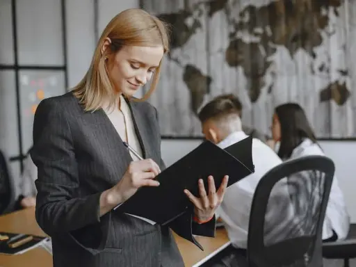 Kobieta w garniturze analizuje dokumenty, przygotowując się do ważnego spotkania. Jej zaangażowanie świadczy o profesjonalnym podejściu do stosunku pracy.