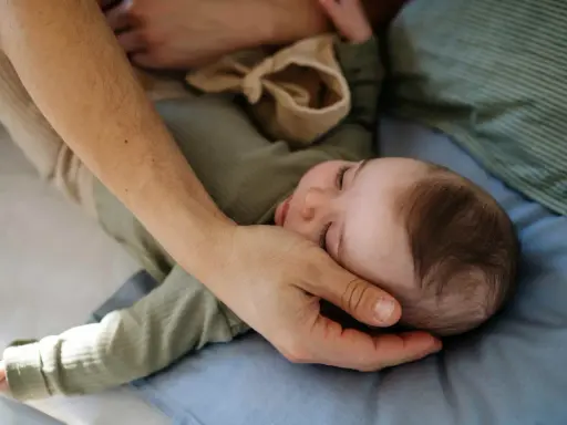 Ręka rodzica delikatnie głaszcze śpiące dziecko, próbując ukoić problemy z zasypianiem u 2 latka.