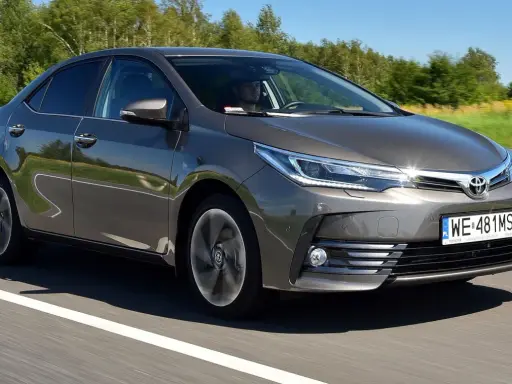 Szara Toyota Corolla E16 jedzie po drodze, za kierownicą siedzi mężczyzna.