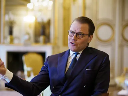 Prins Daniel i mörk kostym, med glasögon, gestikulerar. Rykten om prins Daniel otrogen sprids.