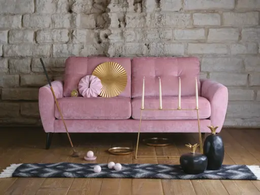 En dyr soffa i sammet, rosa, med dekorativa föremål som en golfklubba, bollar, ljusstakar och ananasskulpturer.
