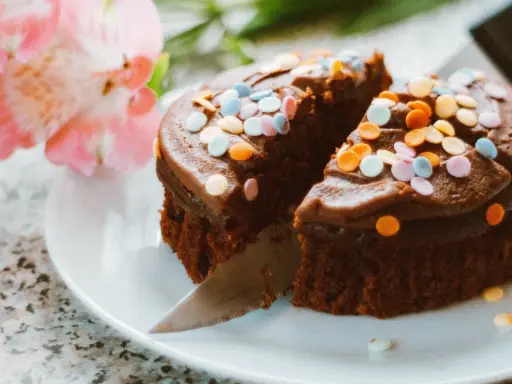 Schokoladenkuchen mit bunten Streuseln, angeschnitten. Eine kreative Idee, um Kuchenreste verwerten und nochmals genießen zu können.