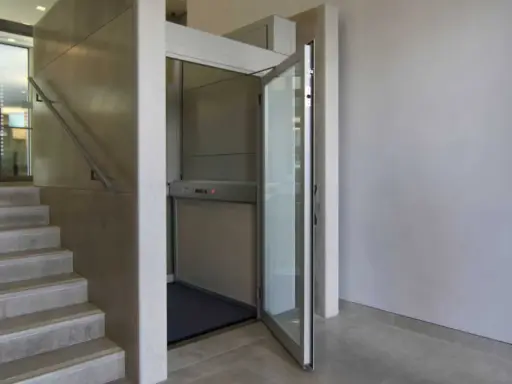 Una piattaforma elevatrice accanto a una scala, una soluzione per chi cerca come abbassare i gradini di una scala, rendendo l'accesso più agevole.
