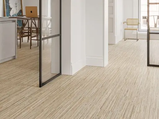 Un moderno revestimiento del suelo de madera clara con un diseño lineal crea un ambiente acogedor en un interior luminoso.