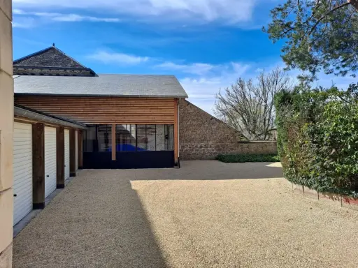 Belle maison tradi pierre Saint Junien avec garage, jardin et ciel bleu.