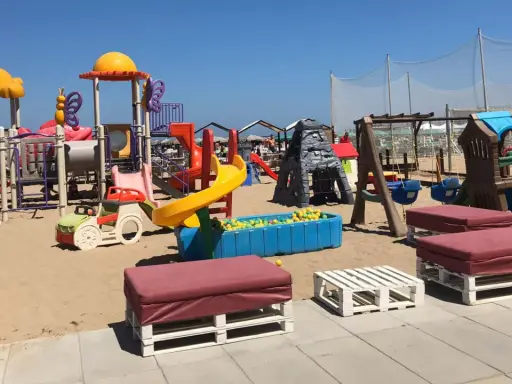 Area giochi per bambini sulla sabbia, con scivoli, altalene e piscina di palline. Un angolo di divertimento al Regina Beach Cattolica.