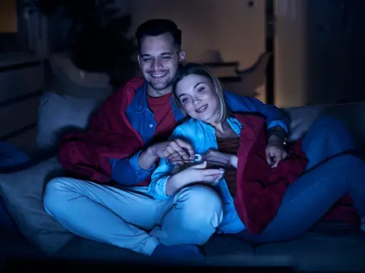 Para spędza miły wieczór, otulona kocem, oglądając lekkie filmy na wieczór i jedząc popcorn.