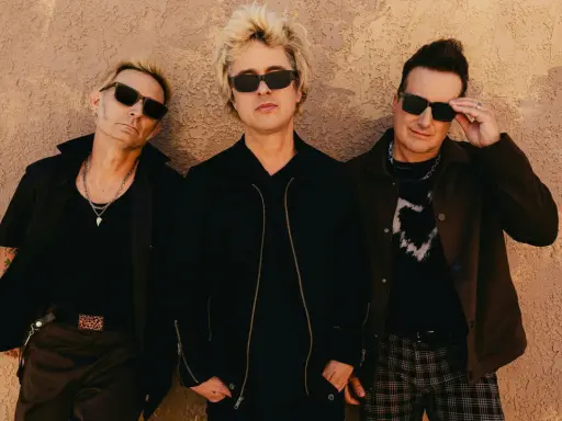 Green Day Sverige: Billie Joe Armstrong, Mike Dirnt och Tré Cool poserar framför en vägg.