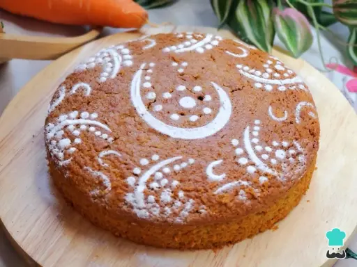 Bizcocho de zanahoria decorado con azúcar glas en un diseño de lunas y puntos. Se ve delicioso y esponjoso.