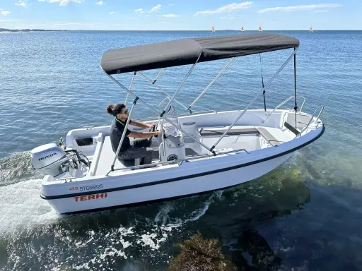 Ce bateau Terhi 450, propulsé par un moteur Honda de 6 cv, navigue sur une mer calme. Idéal pour explorer les côtes.
