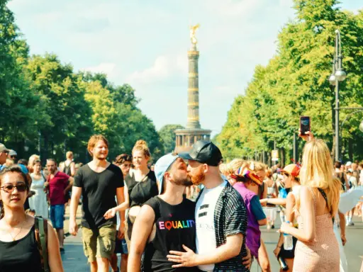 A couple kisses at a pride parade in Germany, with the Victory Column in the background. This scene shows Germany is gay friendly.