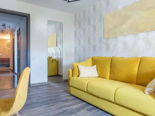 Un sofá amarillo vibrante y un sillón a juego llenan la habitación, destacando los alegres colores de sofás.