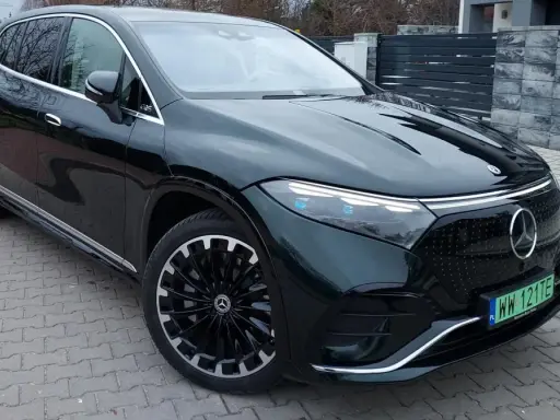 Elegancki, ciemnozielony Mercedes EQS SUV z nowoczesnymi światłami i felgami stoi na podjeździe.